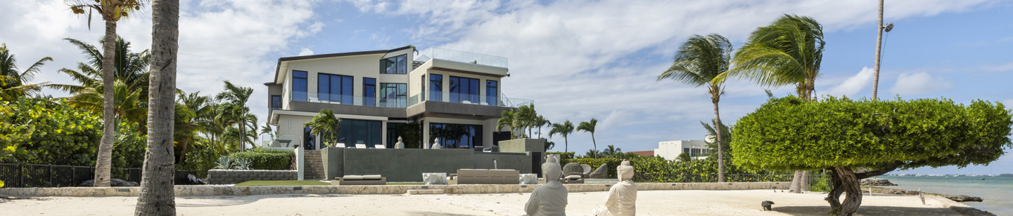House with sea front view surrounded by trees and long gravel pathway towards entrance