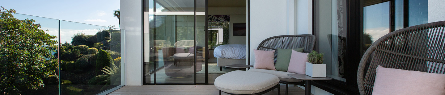 Balcony overlooking trees with round sofas and sliding doors into the house
