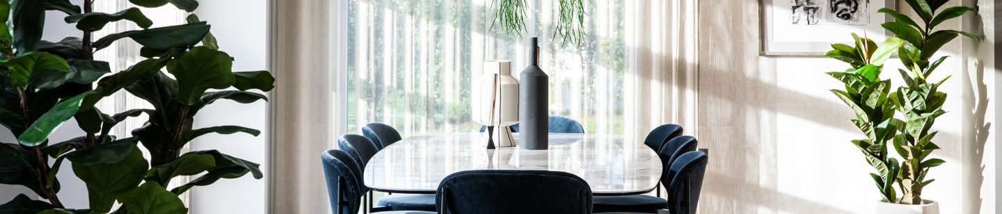 Modern dining room with a stylish table, chairs and surrounded by green plants