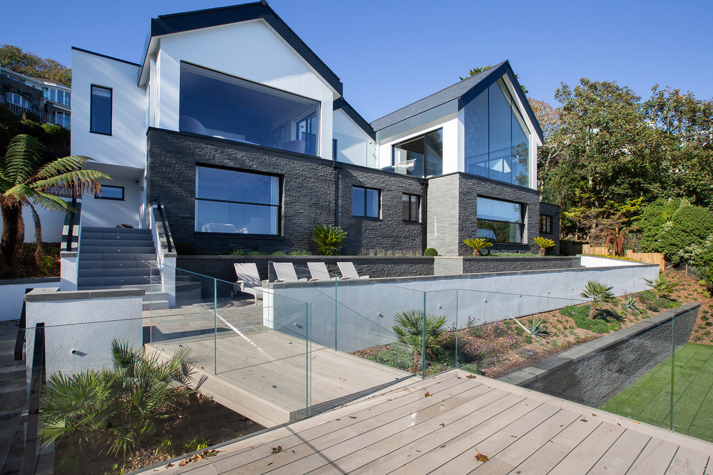 Modern house with decking, deck chairs, and large windows in Fort George