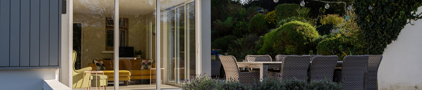 Outdoor photo of a patio with festoon lights, wicker table and chairs, and a conservatory
